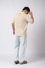 Camisa de punto calado en color beige, de manga corta y corte relajado. Presenta cuello tipo bowling, cierre frontal con botones al tono y una estructura liviana y respirable confeccionada en algodón.