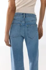 Jean de tiro alto con corte wide leg, confeccionado en denim de algodón con leve elasticidad. Presenta diseño clásico de cinco bolsillos, cierre frontal con botón y acabado en tono azul medio.