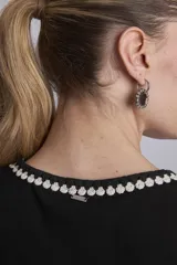 Remera negra sin mangas, tipo musculosa, con escote redondo y ribetes blancos con apliques de perlas en el contorno del cuello y las sisas.