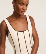 Vestido largo evasê sin mangas de color beige, con escote cuadrado y costuras verticales con bies en tono contrastante oscuro.
