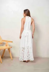 Vestido largo beige con cuello halter y detalle de broderie calado en el dobladillo inferior.