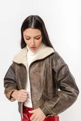 Chaqueta bomber negra de cuero con cuello y solapa de corderito blanco.