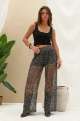 Pantalón largo negro con lentejuelas y acabado brillante, de corte recto y tejido semitransparente.