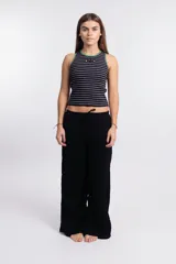 Musculosa corta a rayas horizontales negras y blancas, con cuello y sisas ribeteadas en verde. Presenta un logo ovalado en el pecho.