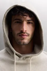 Sudadera con capucha color gris claro, de corte holgado, con bolsillo tipo canguro y cordones ajustables.