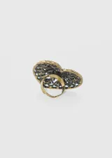 Anillo de aleación de metales color bronce, con forma de corazón calado y detalles de strass color rosa.
