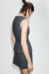 Vestido midi de cuello redondo y sin mangas, confeccionado en tejido con textura. Presenta un diseño que simula dos piezas, con un cinturón integrado a tono y cierre frontal mediante botones forrados.