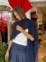 Ruana tejida a mano en hilo de color azul marino, con diseño liviano, textura abierta y terminaciones con flecos en los extremos.