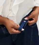 Pantalón de jean raw azul oscuro, corte barrel con piernas anchas y cintura cónica. Presenta costuras contrastantes, cierre tradicional con botón y bolsillos laterales.