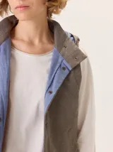 Chaleco con capucha, presenta una espalda de pelo sintético en color marrón oscuro con etiqueta de cuero negra y una capucha de tela tipo denim azul. Diseño original con mezcla de texturas.