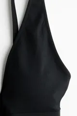 Soutien negro de punto sin costuras, con escote profundo en V y banda elástica ancha en el bajo. Presenta breteles ajustables.
