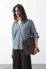 Camisa de algodón con estampado de cuadros vichy en tonos azul y blanco. Presenta escote en V con cierre frontal de botones, mangas largas con puños y un corte levemente holgado con frunces en hombros y espalda.