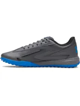 Championes de fútbol Under Armour Shadow Turf 3, diseñados para césped artificial. Presentan una parte superior sintética gris con detalles en azul, entresuela Charged Cushioning para amortiguación y suela de goma con tacos estratégicos para máximo agarre.