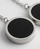 Caravanas colgantes de acero italiano con diseño de doble círculo, uno superior blanco y uno inferior negro, unidos por una cadena fina.