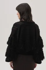 Cárdigan de tejido de punto negro con lurex de colores, detalles calados, trenzas tejidas y flecos en mangas y espalda.