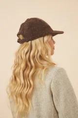 Gorra con visera confeccionada en lana fina sin teñir, con un sutil patrón de tejido en espiga.