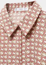 Camisa de corte recto y tejido fluido, con cuello camisero clásico, cierre frontal de botones y mangas largas con puños abotonados.
