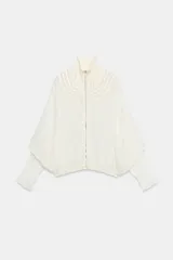 Bomber de viscosa color blanco crudo, de corte holgado, cuello subido y cierre frontal con cremallera. Presenta mangas abullonadas con puños ajustados y detalle de tejido satinado en la parte superior delantera.
