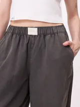 Pantalon de gabardina de corte recto y pata ancha, con cintura elástica y etiqueta decorativa en el frente.