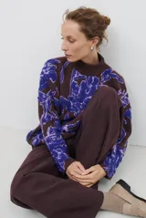 Buzo de tejido de punto con diseño floral en contraste, cuello redondo y mangas largas. Presenta una textura suave y un corte holgado.