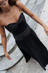 Pollera larga de corte evasé en color marrón, con detalles de costuras verticales y una banda ancha en la cintura con textura brillante.