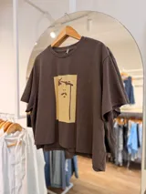 Remerón marrón de algodón, de corte oversize y mangas cortas, con estampa gráfica minimalista en tono beige en el frente.