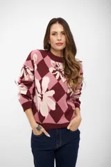 Buzo de tejido de punto con diseño de rombos y flores estampadas en tonos bordó, rosa y crema. Presenta cuello redondo, mangas largas y puños acanalados.