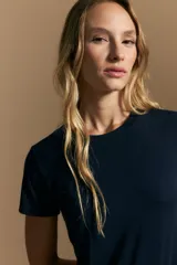 Remera básica de manga corta con cuello redondo y silueta ajustada, confeccionada en una mezcla de lyocell y elastano que proporciona una textura suave, liviana y elástica.