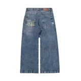 Pantalón de denim azul desgastado, corte mega baggy con piernas anchas y bolsillos traseros grandes. Presenta un bordado dorado en estilo gótico en el bolsillo trasero izquierdo.