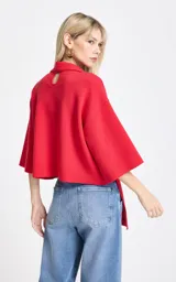 Blusa de punto color rojo con diseño de cuello asimétrico que incorpora una bufanda integrada. Presenta mangas anchas de largo tres cuartos y un corte holgado.