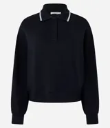 Buzo cerrado de corte holgado confeccionado en tejido de viscosa y poliéster, color verde oliva. Presenta cuello polo con detalle de línea contrastante en el borde, cierre frontal parcial con botones y mangas largas con puños ajustados.