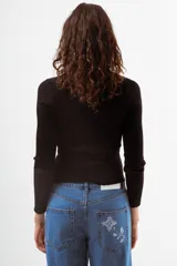 Top de tejido de punto acanalado color bordó, de manga larga y cuello polo con botones frontales.