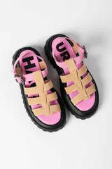 Sandalia tipo gladiadora con plataforma track negra. Presenta un diseño bicolor con tiras delanteras en color amarillo neón y talón con tira ajustable en color beige. Incluye hebilla metálica negra.