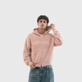Sweater tejido de punto color rosa con capucha, cierre frontal completo y diseño de doble cursor. Presenta detalles de terminaciones desflecadas en el ruedo y los puños, con un logo bordado en relieve en el pecho.