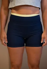 Calza corta deportiva color azul marino, tiro alto, con pretina ancha de color amarillo claro y un pequeño logo bordado en la parte trasera central superior.