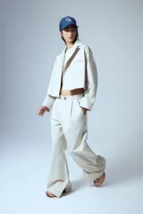 Pantalón sastrero de gabardina color beige, con pinzas delanteras, presillas anchas en la cintura y tajo interno en la botamanga.
