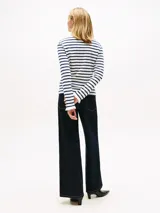 Remera de manga larga con cuello barco y diseño de rayas horizontales en azul marino y blanco. Presenta un pequeño logo bordado en el pecho y puños con detalle de volado.