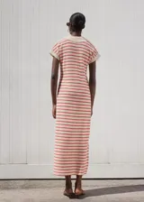 Vestido largo de punto fino con diseño recto, cuello camisero con escote en pico y mangas cortas. Presenta un patrón de rayas horizontales en color rojo sobre base crema.