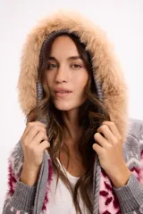 Buzo de punto con cierre frontal, diseño de jacquard con motivos geométricos en tonos gris, rosa y bordó. Cuenta con capucha desmontable con borde de piel sintética y cordones decorativos con borlas.