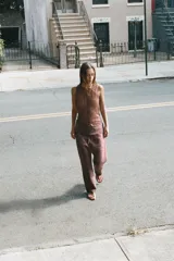 Top de punto confeccionado en hilatura con mezcla de viscosa, color marrón, con cuello redondo y diseño sin mangas. Presenta un tejido con efecto arrugado y cierre frontal con botones.