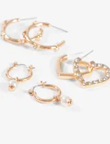 Set de tres pares de aros plateados: un par con forma de corazón con strass, un par tipo argolla con apliques y un par tipo argolla con dije de perla.