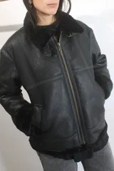 Campera tipo bomber de cuero genuino color negro, con interior y cuello de piel sintética negra. Presenta cierre frontal metálico, bolsillos laterales y puños con terminación en tejido acanalado.