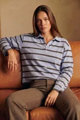 Sweater tipo polo de manga larga con diseño de rayas horizontales en tonos celeste y marrón oscuro. Presenta cuello camisero con abertura frontal y corte recto.