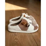 Pantuflas de peluche con diseño de vaca, confeccionadas en piel sintética suave. Cuentan con suela de goma antideslizante y diseño abierto en el talón.