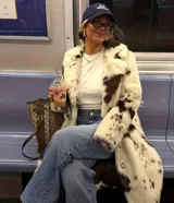 Tapado midi de piel sintética con estampado de manchas tipo vaca en tonos blanco y marrón. Presenta cuello amplio, cierre frontal con botones y corte recto de ajuste relajado.