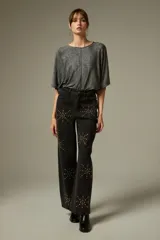 Pantalón de jean negro de corte ancho y tiro alto, decorado con aplicaciones de strass formando estrellas en toda la superficie.