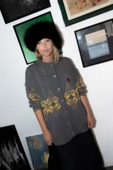 Saco de punto gris con diseño geométrico en color amarillo, cierre frontal con botones, cuello redondo y bordado de corazón pequeño en el pecho.