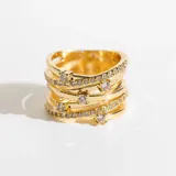 Anillo dorado ancho con diseño calado y entrelazado, con cristales claros.