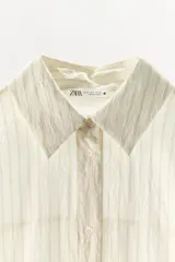 Mono corto camisero de mezcla de lyocell con estampado de rayas finas, cuello solapa, manga larga y cierre frontal con botones. Presenta cintura elástica y detalles de encaje en el bajo.
