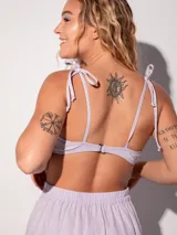 Top de bikini negro brillante con tirantes finos ajustables y cierre trasero con broche.